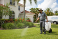 Pest control technician spraying Florida lawn and plants